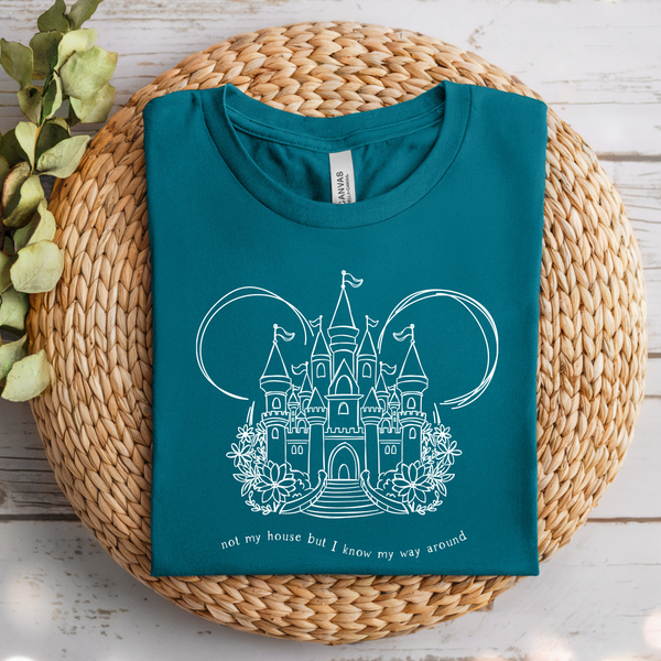 Teal shirt with castle design on a woven mat